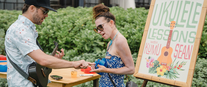 woman being taught how to play the ukulele